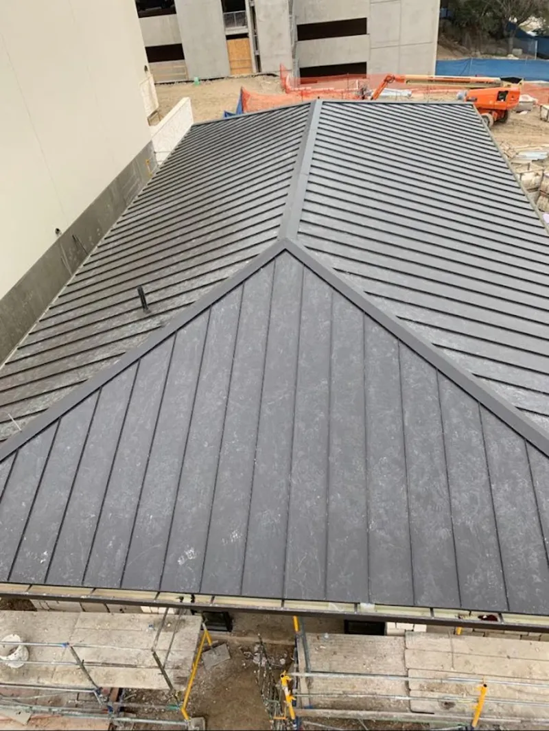 Commercial metal roof construction with crane equipment in Portland